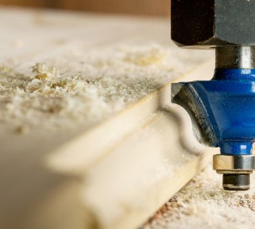 Nahaufnahme eines Fräsers, der die Kante eines Holzbretts formt.